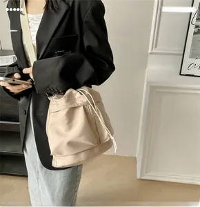 Detail of beige nylon drawstring bucket bag with slim shoulder strap and pleated texture