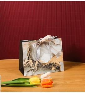 Detail of luxury marble gift bag with gold foil accents and grey satin ribbon handles