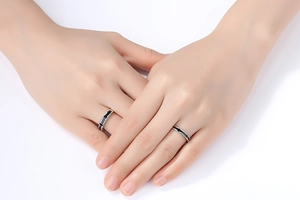 Close-up of minimalist couple rings with zircon crown design on a model hand