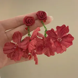 Detail of red fabric flower earrings with rose stud and teardrop crystal pendants