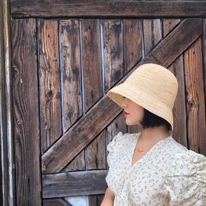 Close-up of a hand-woven beige raffia bucket hat featuring a dense weave and sun protection