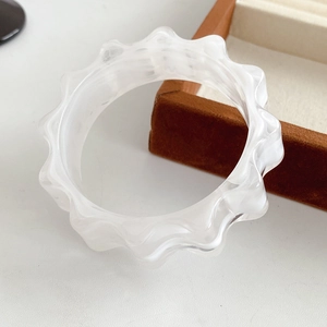 Detailed view of wave-shaped translucent resin bangle with unique marble texture