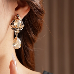 Close-up of vintage champagne teardrop crystal earrings worn with refined metal details