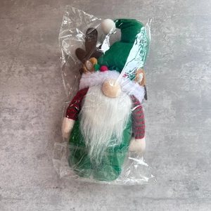Detailed view of a Christmas gnome doll with green hat and white beard in clear packaging