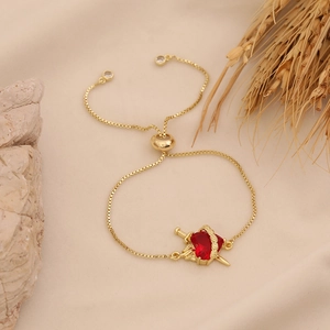 Macro shot of red heart gemstone bracelet with golden sword detail on warm background