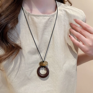 Detail view of ethnic resin pendant necklace on a beige linen top for women