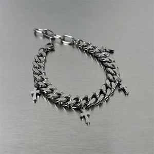 Silver Cuban link bracelet with four cross pendants on a brushed metallic background