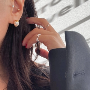 Detail showing minimalist pearl earrings and silver ring styled with a black suit