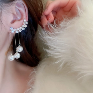 Detail of elegant gold ear cuff with dangling pearl tassels and sparkling zircons