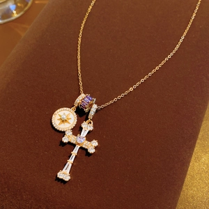 Detail of 18k gold cross necklace with zircon heart and shell star charms