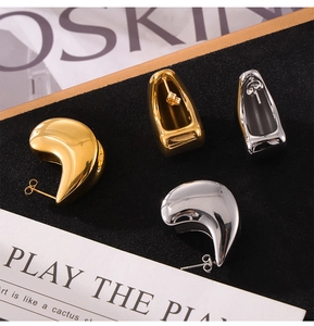 Detail of gold and silver teardrop earrings on black velvet with polished mirror finish