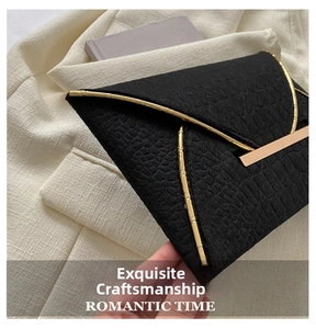 Détail de la pochette noire à motif crocodile avec cadre doré aspect bambou