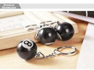 Detailed view of polished resin black number 8 pool ball keychain on wood background