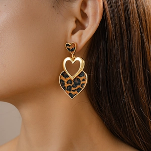 Close-up of leopard print heart earrings in gold finish worn by a model for a vintage look