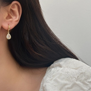 Detailed view of pear-cut zircon drop earrings with gold plating and pavé crystal edges