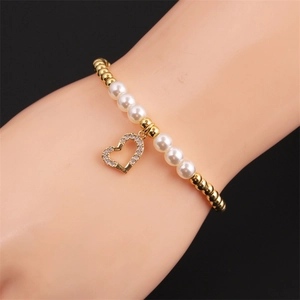 Close-up of heart-shaped zircon charm on gold-plated pearl bracelet for women