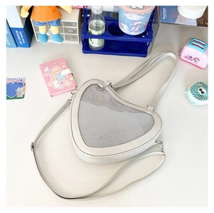 Close-up of white heart-shaped Ita bag with mesh window on a decorated desktop
