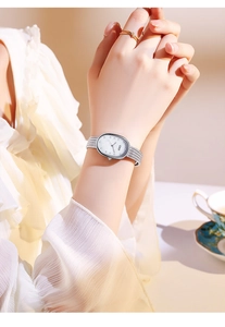 Close-up of silver oval watch with mother of pearl dial and mesh band on wrist