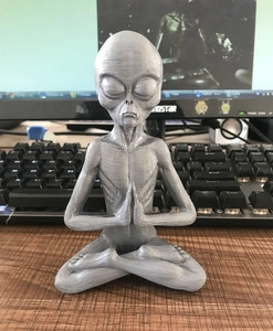 Macro shot of 3D printed meditating alien resin statue showing layered texture and matte finish