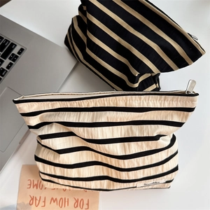 Close-up of canvas striped cosmetic bags with metal zippers in a lifestyle desktop setting