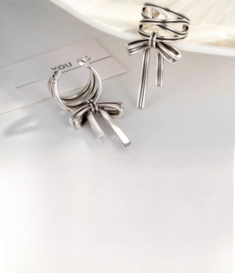 Detail of silver bow ear cuff with long ribbon dangles in a vintage aesthetic