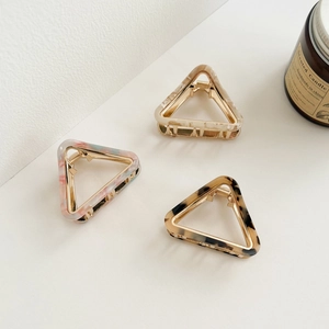Detailed close-up of triangle acetate hair claws in tortoise shell and marble patterns