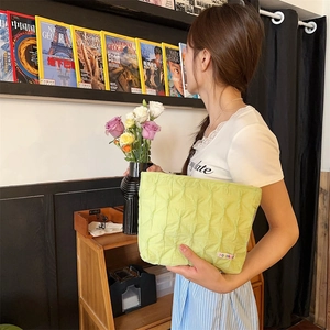 Dettaglio della pochette in tessuto trapuntato verde chiaro con etichetta colorata