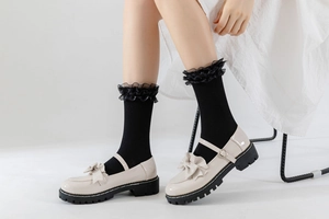 Détail de chaussures Mary Jane blanches et chaussettes noires avec dentelle en organza