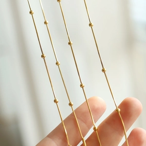 Detail of multiple gold-plated snake bone necklaces with small round bead accents