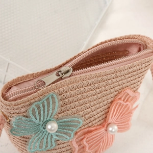 Close-up of pink woven bag with lace butterflies, pearls and metal zipper detail