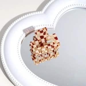 Macro view of checkered pattern hair claw clip on heart-shaped mirror tray