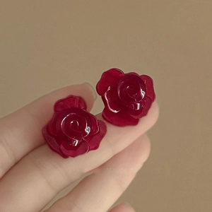 Detailed macro view of dark red rose petal earrings with a glossy resin finish