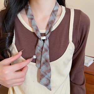 Detail of a brown plaid chiffon scarf necklace with a white buckle fastener