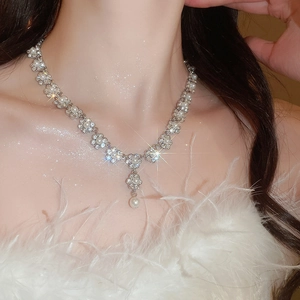 Close-up of Y-shaped silver necklace with flower rhinestones and hanging pearl pendant