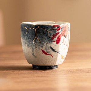 Hand-painted blue ceramic teacup with gold rim and carp lotus motif on wooden table