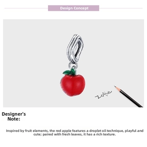 Macro detail of red enamel apple charm with green leaves and twisted silver connector