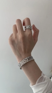Detailed close-up of multilayer silver zircon cuff bracelet and matching ring on model wrist