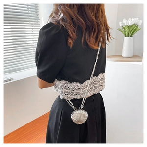 Detailed close-up of shell-shaped pearl crossbody bag with elegant faux pearl chain strap