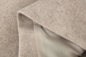 Close-up detail of premium oatmeal wool blend fabric with high-quality stitching texture