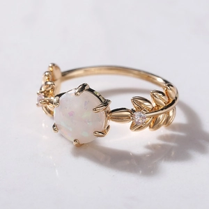 Macro di anello a foglia in oro con opale e diamanti su sfondo di marmo bianco