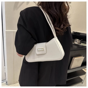 Detailed back view of a chic cream-colored baguette bag worn on a model's shoulder