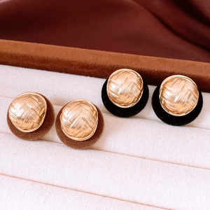Close-up of vintage button earrings with woven gold texture and black velvet trim