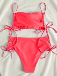 Detailed flat lay of coral pink two-piece bikini with side drawstring hollow details