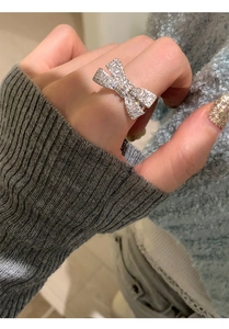 Detailed view of a silver bow ring with sparkling zircons worn on a model's finger