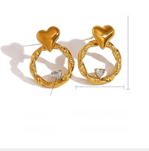 Macro detail of gold-plated stainless steel heart earrings with sparkling crystal accents