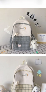Close-up of plaid school backpack showing bow details and cute plush bear pendant