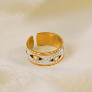 Bague ouverte Evil Eye dorée avec émail blanc sur fond de velours chaleureux