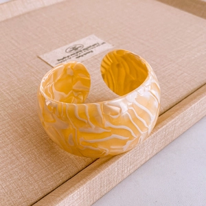 Macro shot of wide open bangle with vintage branch texture and yellow marble pattern
