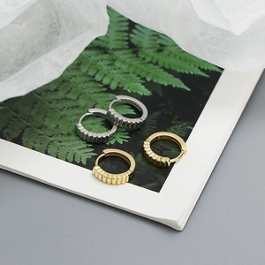 Macro detail of gold and silver S925 sterling silver hoop earrings with vertical textures