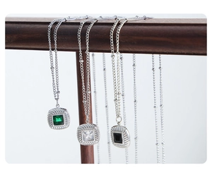 Detail of square vintage pendant necklaces with emerald, clear, and black glass stones